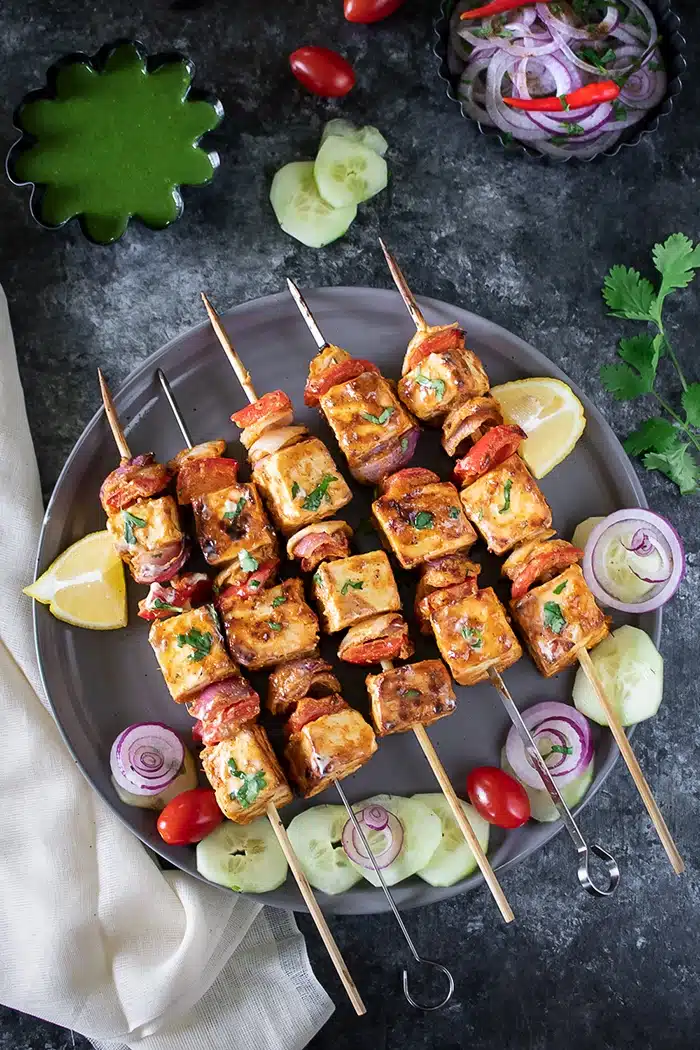 Achari Paneer Tikka on skewers with chutney and onions 