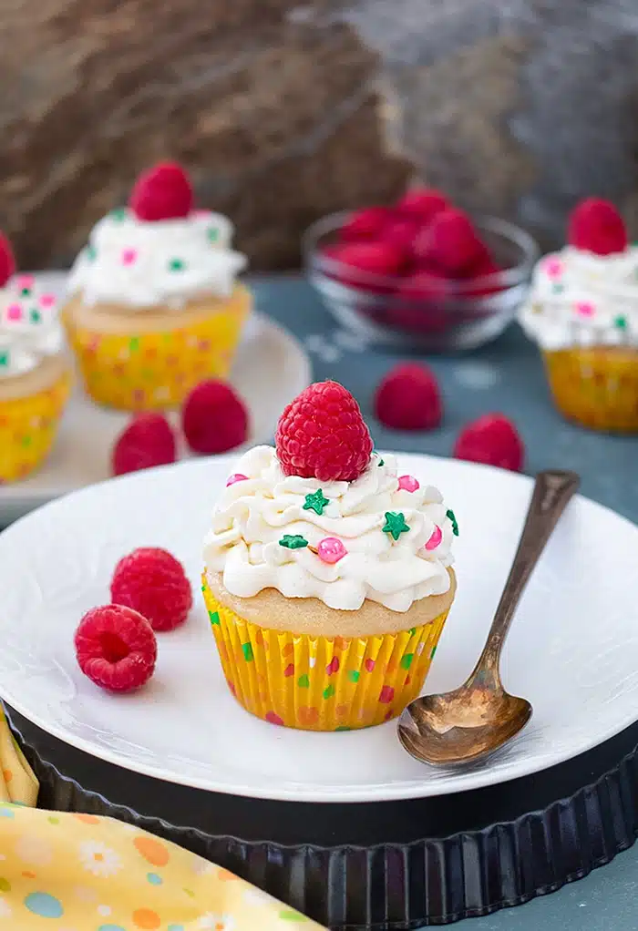 Eggless vanilla cupcake with white frosting and raspberry on top