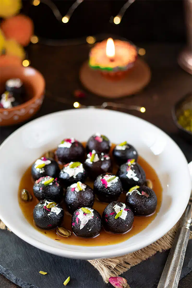 Kala Gulab Jamun in a plate garnished with edible silver foil