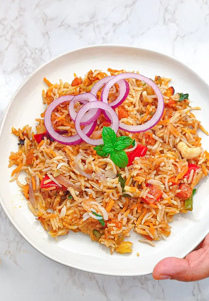 Vegetable Biryani on white plate with onion rings