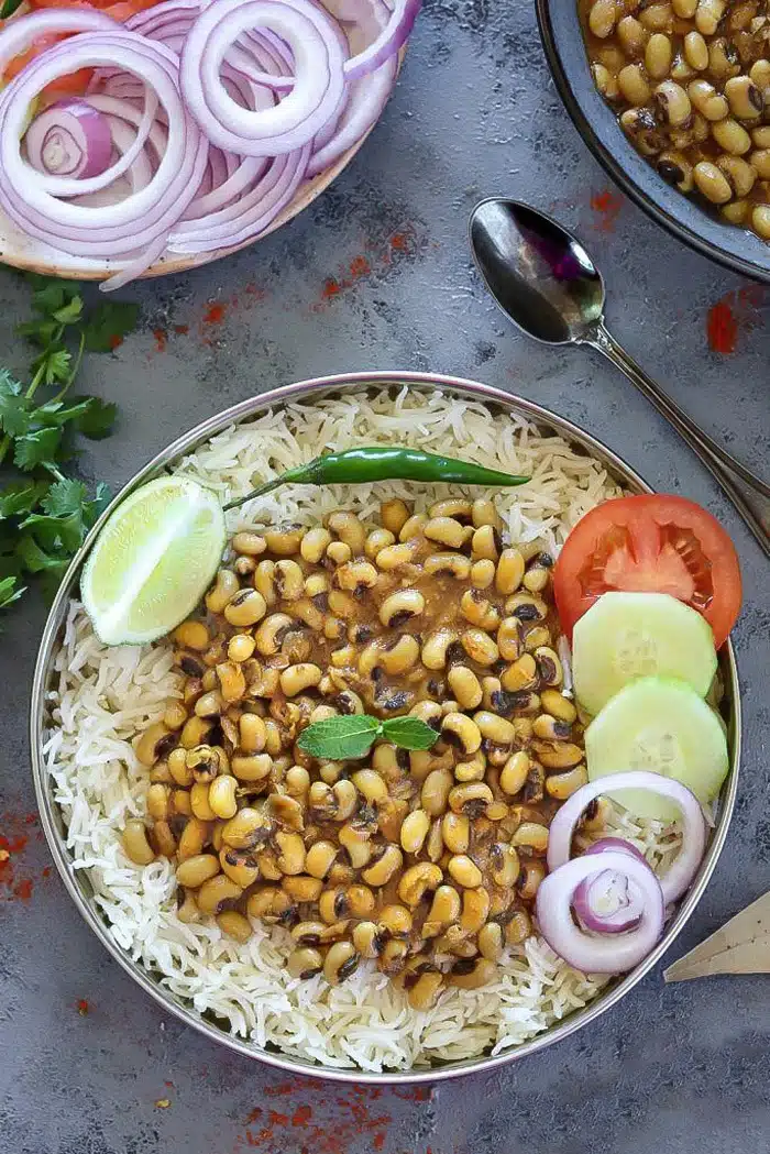 Instant Pot Black Eyed Peas Curry in a plate with rice and salad on side- Ruchiskitchen