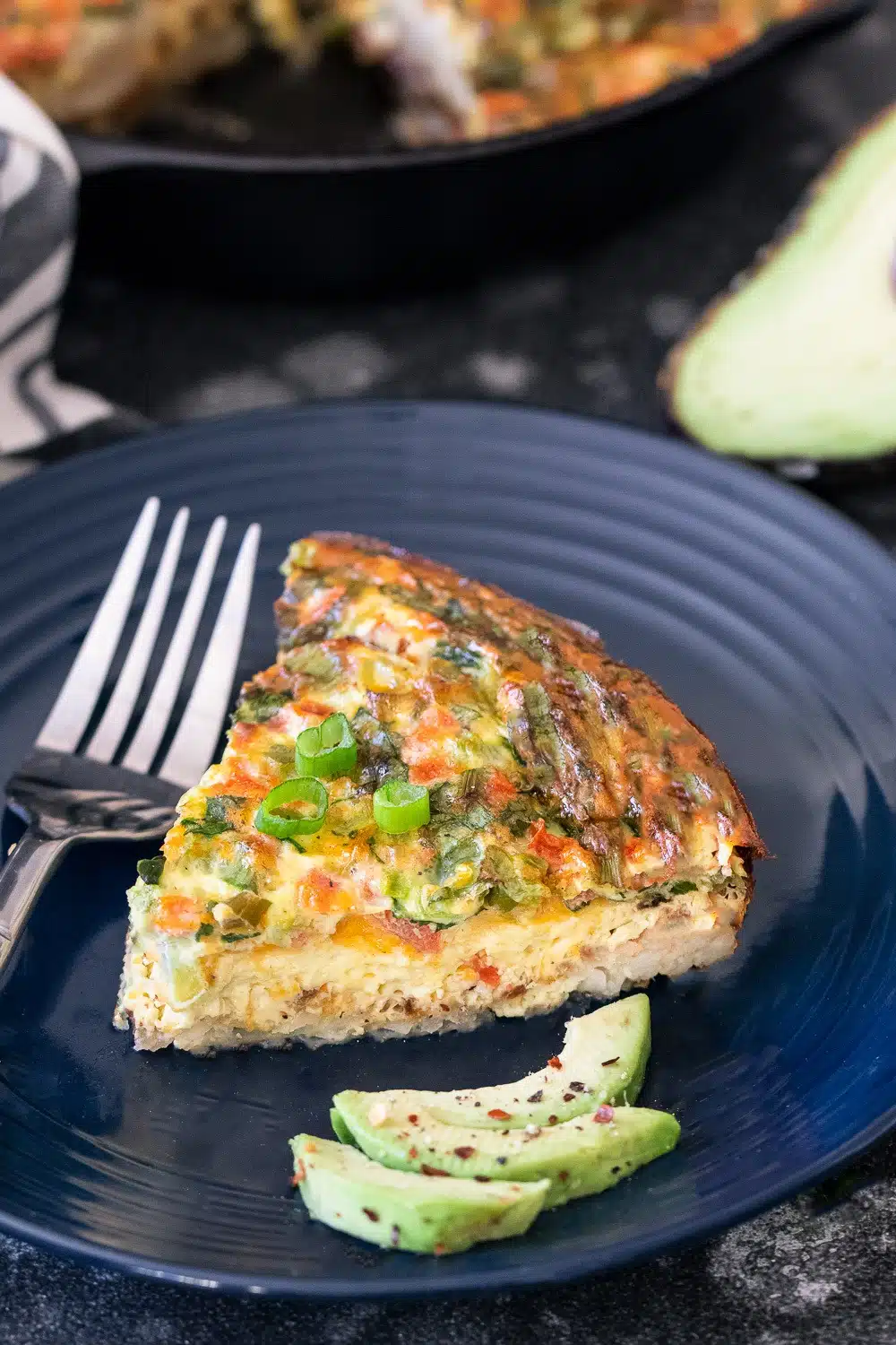 Hash Brown Frittata wedge on a blue plate with fork and avocado slices