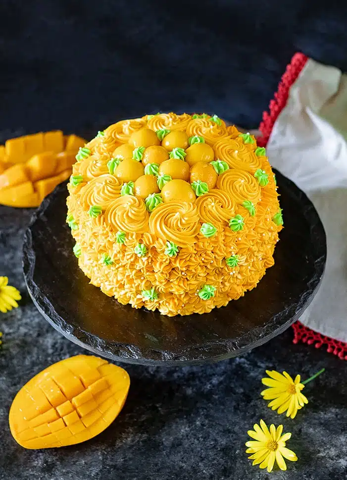 Eggless mango cake with frosting and fresh mangoes