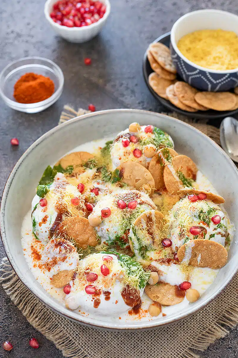 Bhalla papdi chaat arranged on a plate drizzled with curd and spices